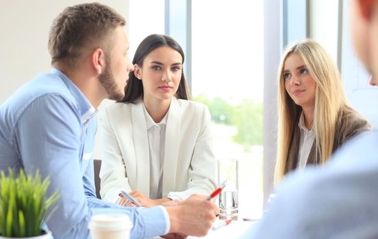 A group of business people at a meeting on the background of office. Focus on a beautiful brunet