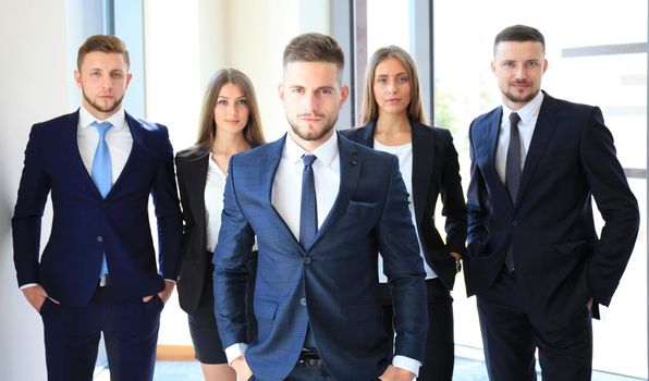 Young businessman standing in office with his collegue on the background