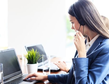 Portrait of call center worker accompanied by her team. Smiling customer support operator at work.