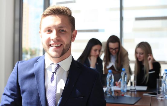 Happy smart business man with team mates discussing in the background