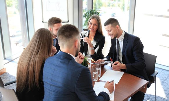 A group of business people at a meeting on the background of office. Focus on a beautiful brunet