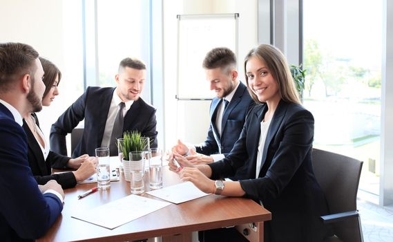 A group of business people at a meeting on the background of office. Focus on a beautiful brunet