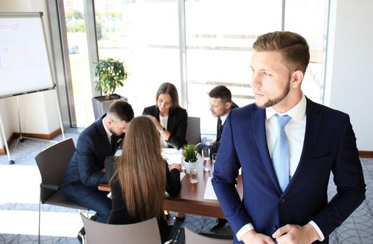 Young businessman standing in office with his collegue on the background