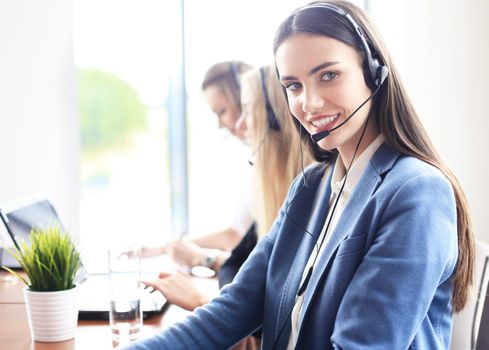 Portrait of call center worker accompanied by her team. Smiling customer support operator at work.