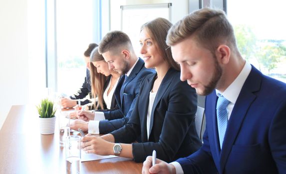 Smiling businesswoman looking at camera at seminar with her colleagues near by