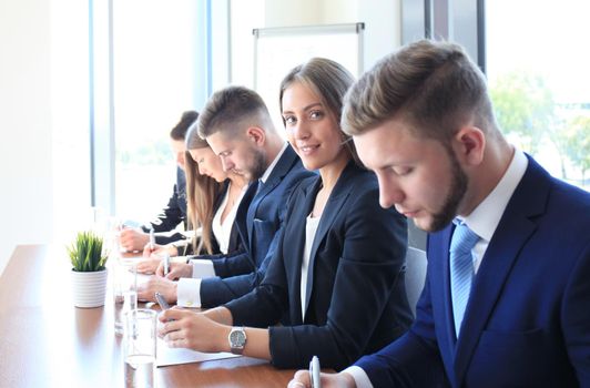 Smiling businesswoman looking at camera at seminar with her colleagues near by