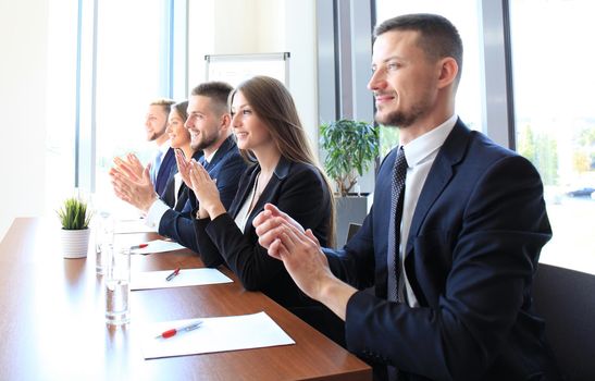 Photo of happy business people applauding at conference, focus on smiling girl