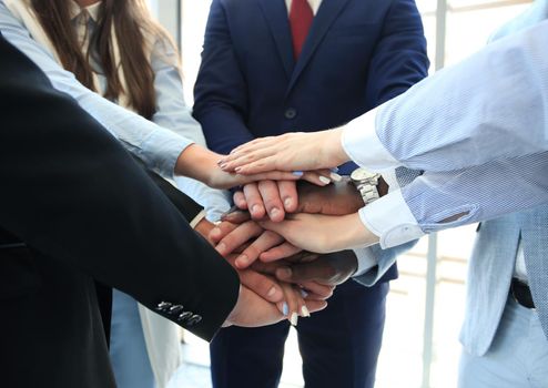 Multiethnic group of young people putting their hands on top of each other. Close up image of young business people making a stack of hands.