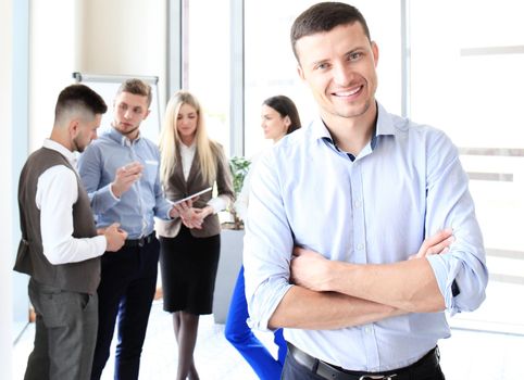 Happy smart businessman with team mates discussing in the background