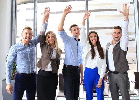 Portrait of successful business group waving hands in office