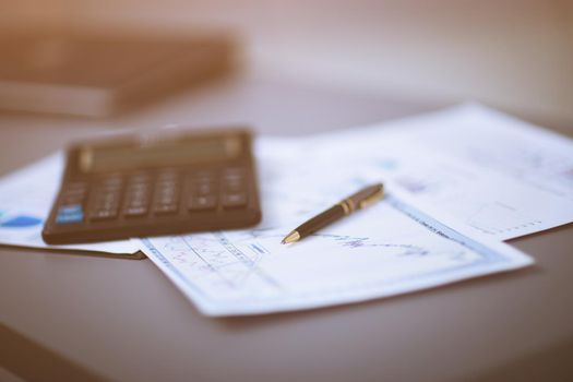 Business graph analysis report. Accounting, on the documents lay calculator and pen