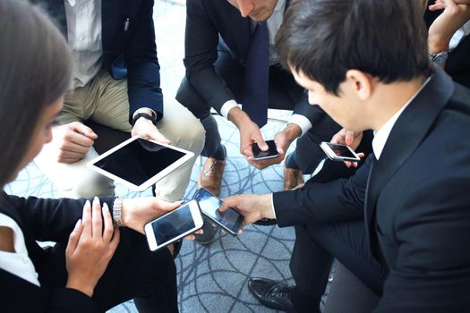 Group of people using smart phones sitting at the meeting.