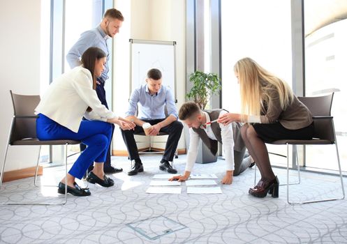 Creative people looking at project plan laid out on floor. Business associates discussing project plan in modern office.