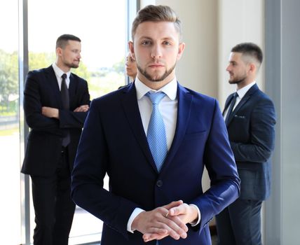 Young businessman standing in office with his collegue on the background