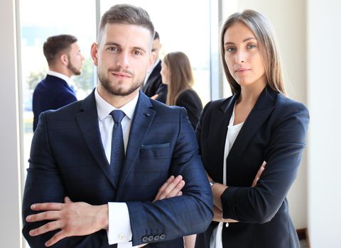 Young businessman standing in office with his collegue on the background