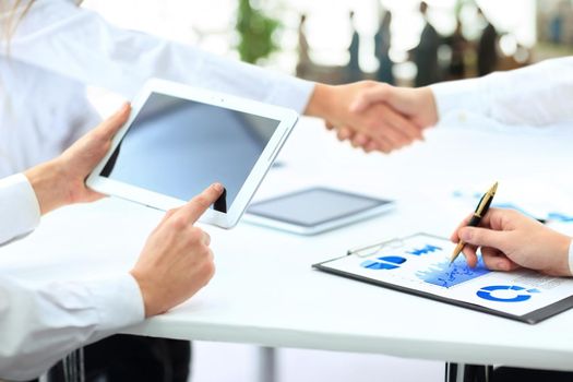 business team with tablet and documents on the background of business partners handshaking