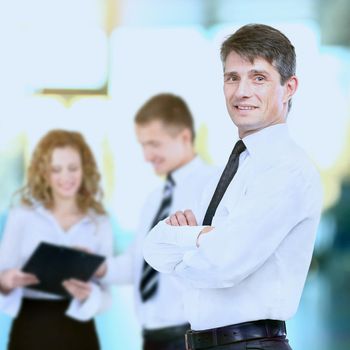 Successful business man standing with his staff in background at office