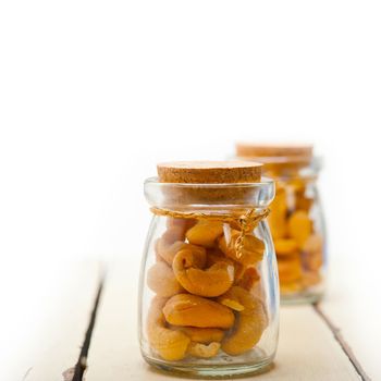 cashew nuts on a glass jar over white rustic wood table 