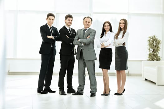 successful business team on the background of bright, modern office in a full-length, smiling and looking at the frame