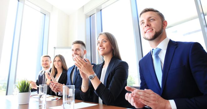 Photo of happy business people applauding at conference, focus on smiling girl