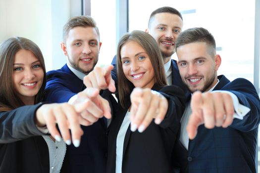 Portrait of excited young business people pointing at you