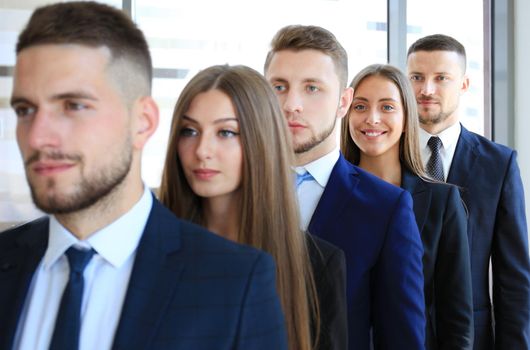 Happy smiling business team standing in a row at office