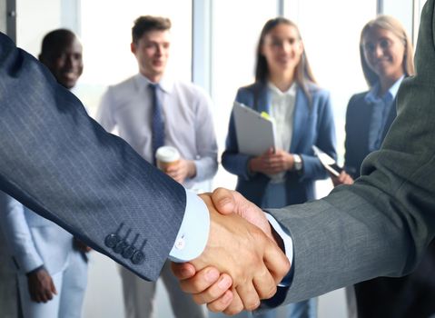 Business associates shaking hands in office