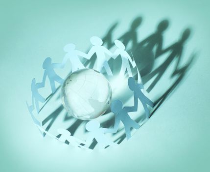 Paper people standing in a circle around glass globe