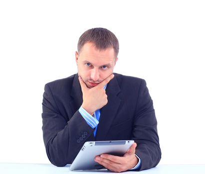 Closeup of a young smiling business man sitting at his office and using his modern tablet pc to do his work