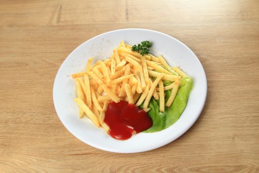 fries potatoes with sauce on a white plate on wooden background