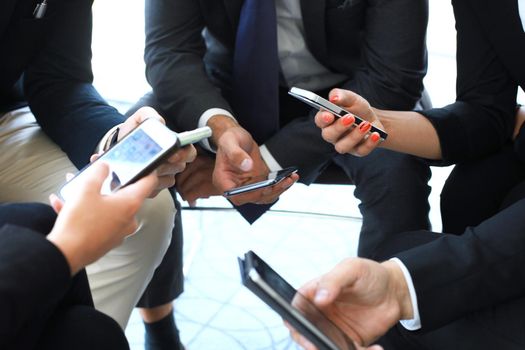 Group of people using smart phones sitting at the meeting.