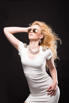 Portrait of a beautiful blonde girl in dark glasses on a black background