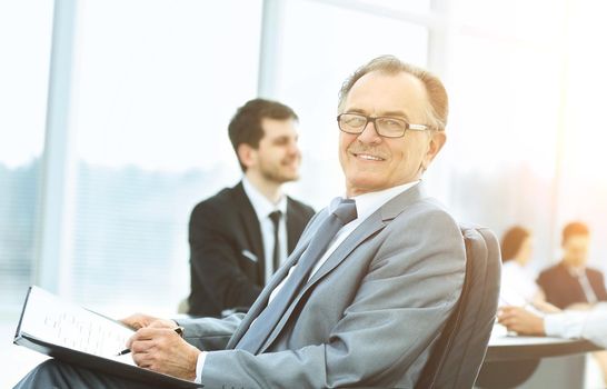 Portrait of a successful businessman in the office on the background of working business team in a modern office