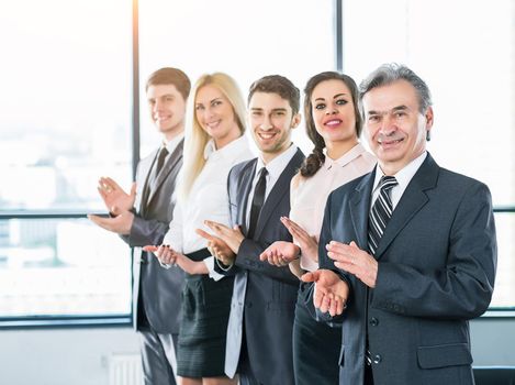 Happy business group applauding the company's success in the office