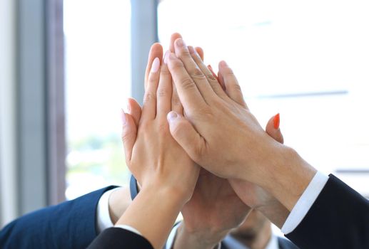 Business team joining hands together standing in office.
