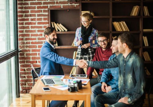 handshake business partners at a meeting in creative office on the background of business team