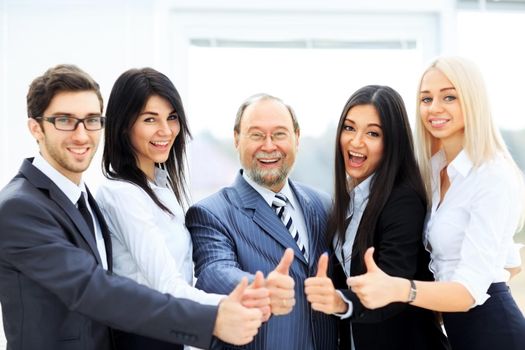 successful friendly business team on office background all showing thumbs up