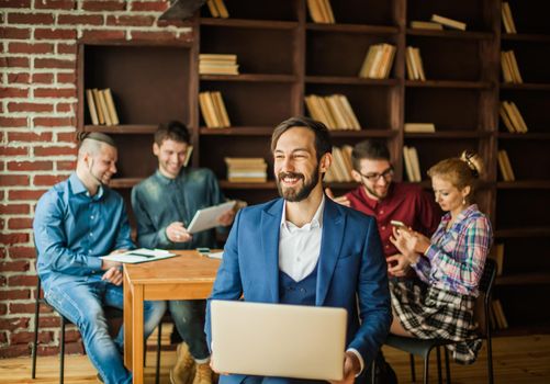 successful employee of the firm with a laptop and a business team discussing the current problems of the company