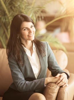 Beautiful business woman. Resting on the couch after a deal smiling and posing to the camera
