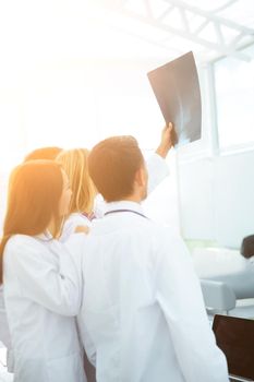 closeup of a group of doctors-surgeons in white coats looking at x-ray after the surgery and discussing the patient's diagnosis