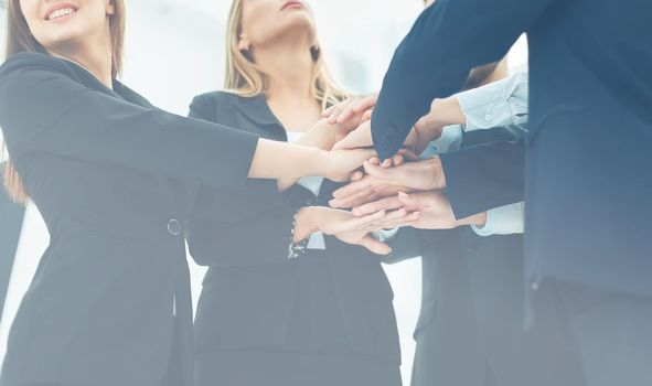 closeup of business team standing in a circle shaking hands with each other.