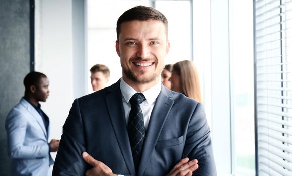 Young businessman standing in office with his collegue on the background