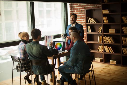 group of creative designers discussing a new color palette in the workplace in a modern office