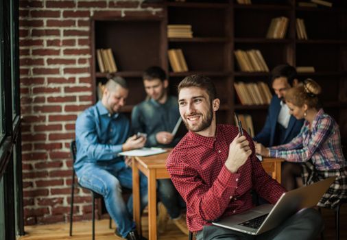successful employee of the company with laptop on the background of business team.the photo has a empty space for your text