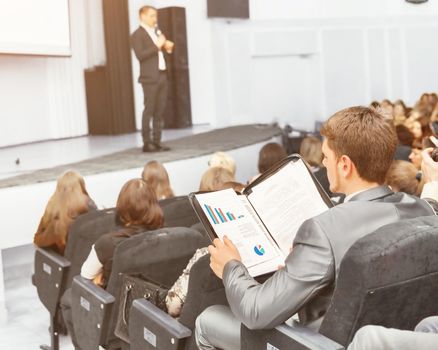 Speaker at a business convention and presentations. The audience sitting businessman and analyzes done by the report and prepares for performance
