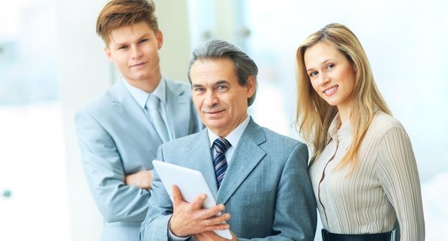 Boss and business team on office background standing in a wedge behind the leader