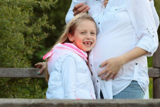 pregnant mom,happy father and little daughter on a walk in the Park on a Sunny day.