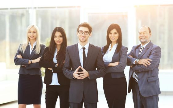 Boss and business team on office background standing in a wedge behind the leader