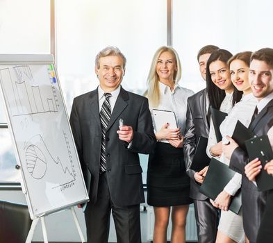 A group of businessmen discussing the policies of the company in the office using a stand with charts
