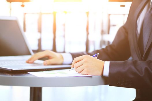 Close-up of male hands with pen and laptop in office